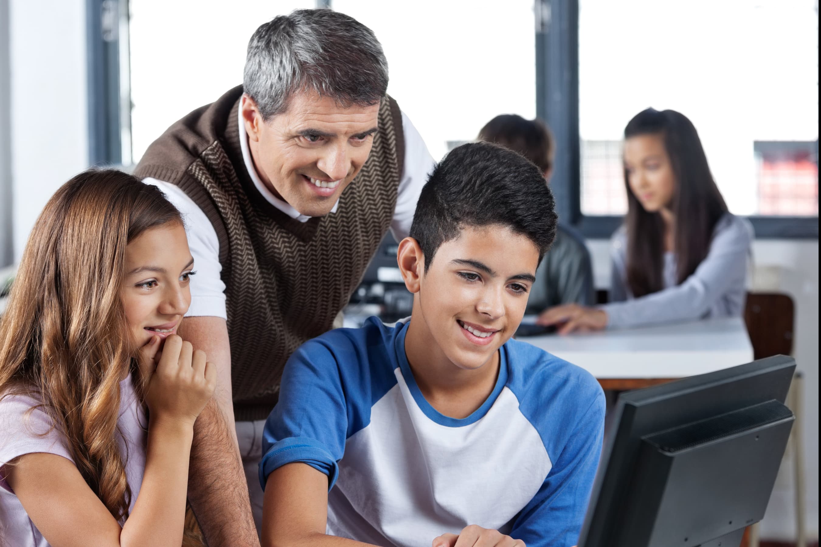 Computer teacher teaching students in computer lab